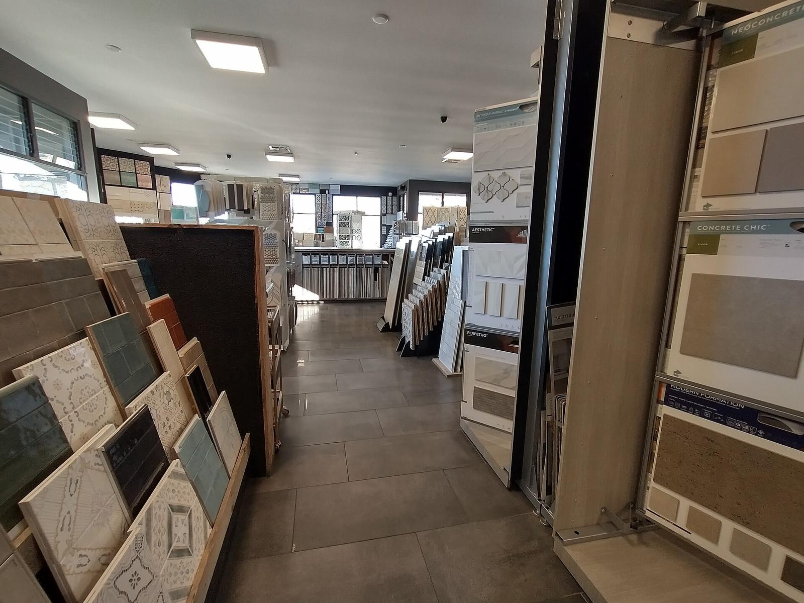 Tegelwinkel met rekken vol wand- en vloertegels en draaibare panelen met tegelstalen